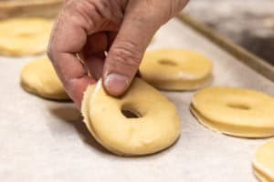 Putting donuts on a pan to rise