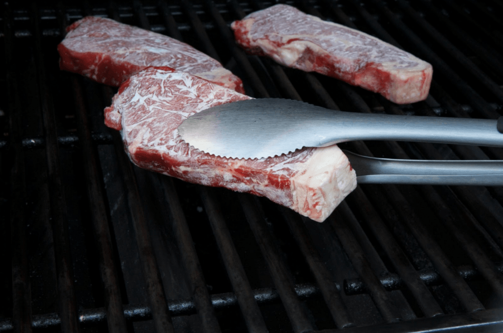 Cooking frozen steak on a grill. 