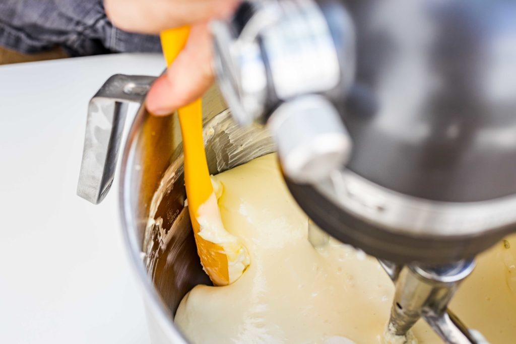 Scraping down the bowl sides helps ensure an even, smooth texture in the cheesecake.