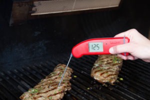Spot-checking doneness temperature of skirt steak with a Thermapen.