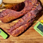 Dry rubbed ribs on a cutting board with thermometers