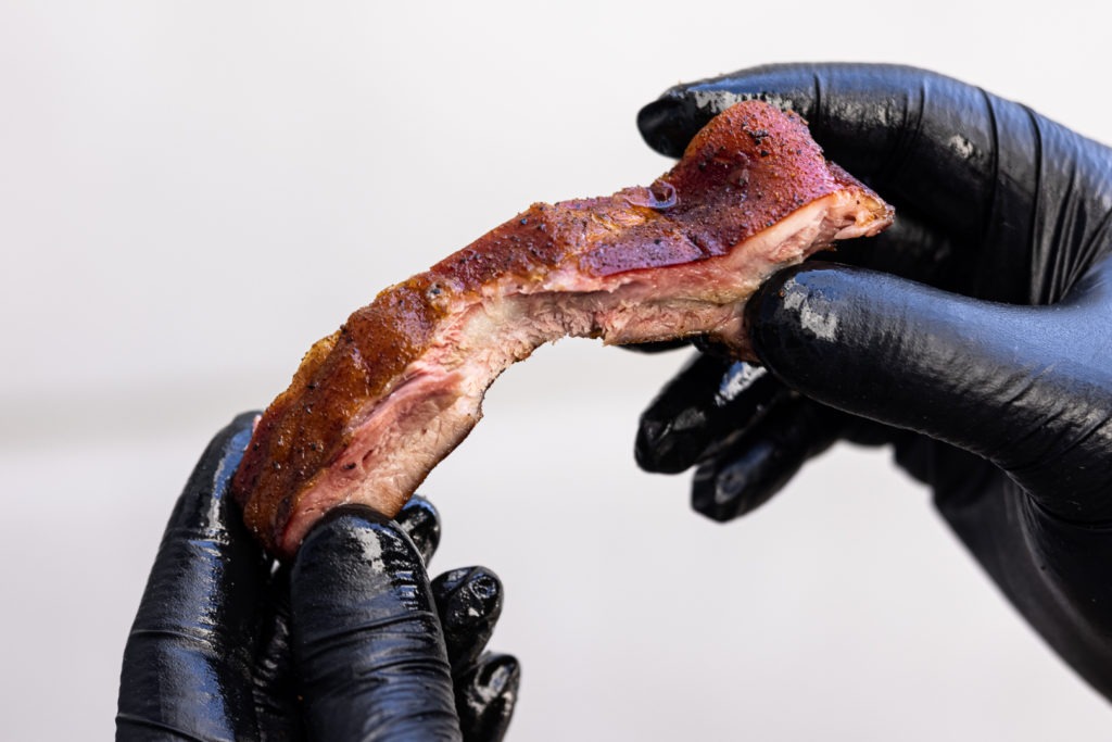 A baby back rib with one bite taken from the meat