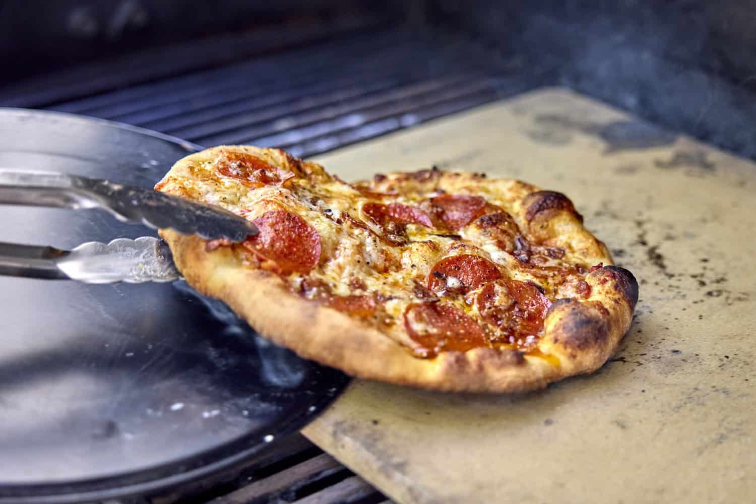 Removing grilled pizza from the grill