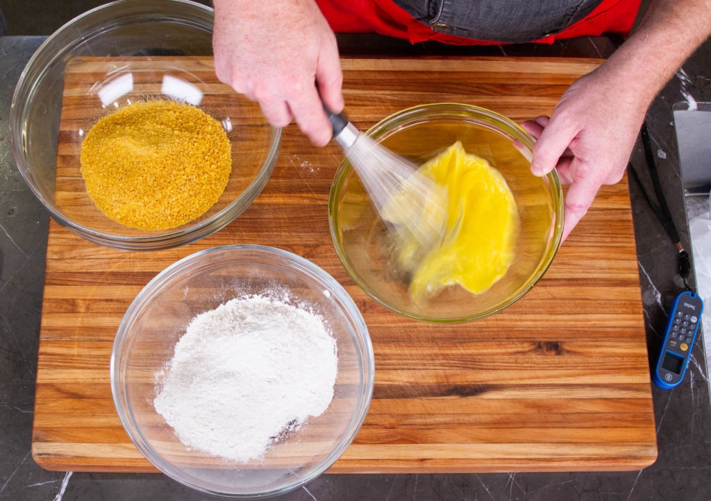 Prepare your bowls for breading: cornflakes, flour, and beaten egg.