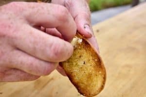 Grating the garlic onto the surface of the bread