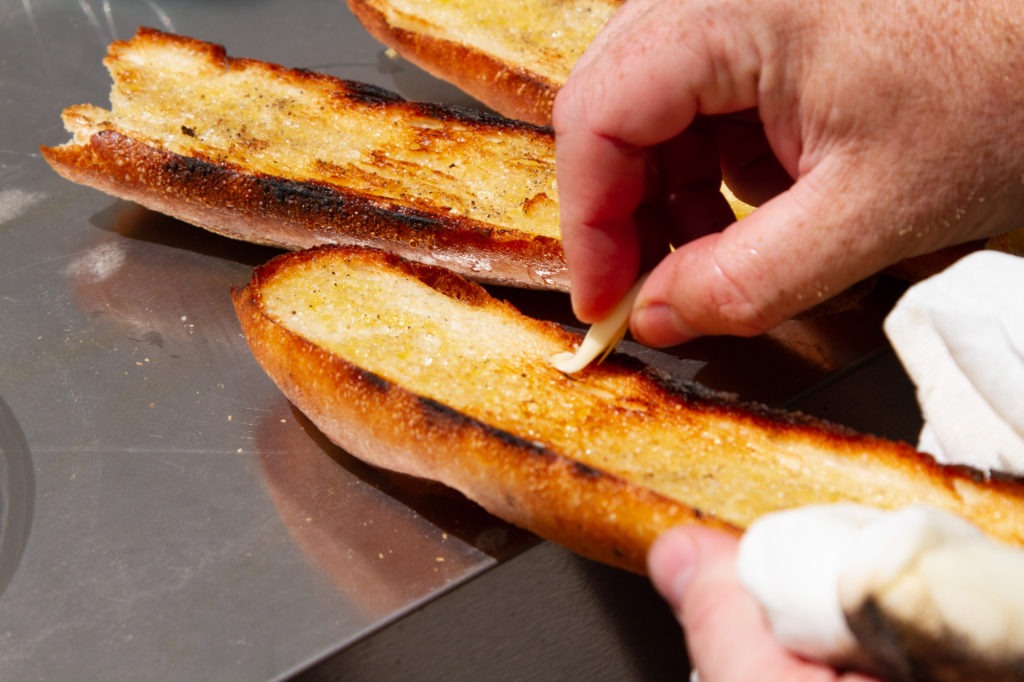 Grate the fresh garlic on the crusty, toasty bread
