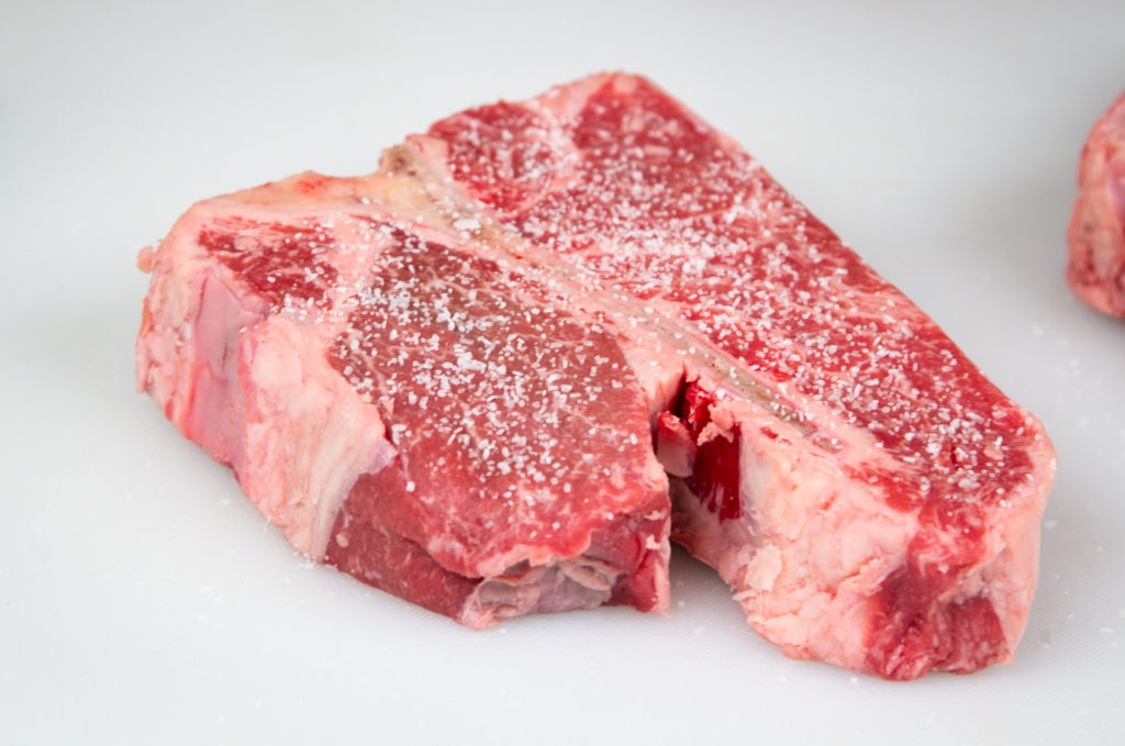 Porterhouse steak, salted to prepare for grilling