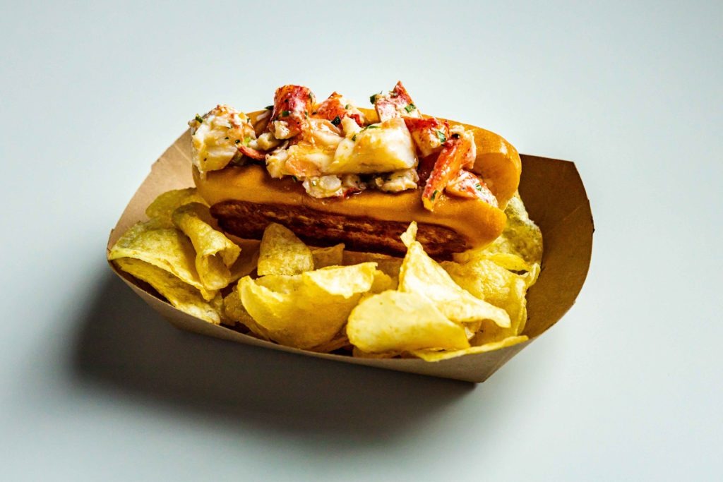 A lobster roll served with thick cut potato chips.