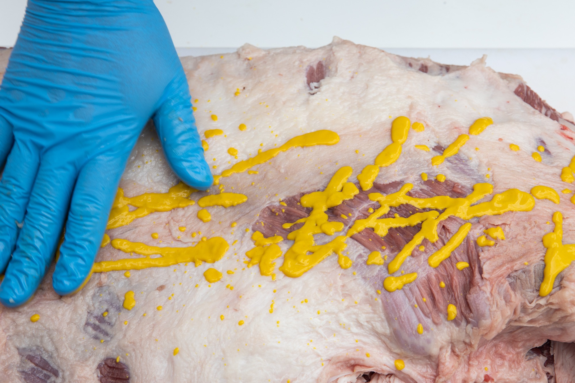 Applying yellow mustard as a binder to the brisket