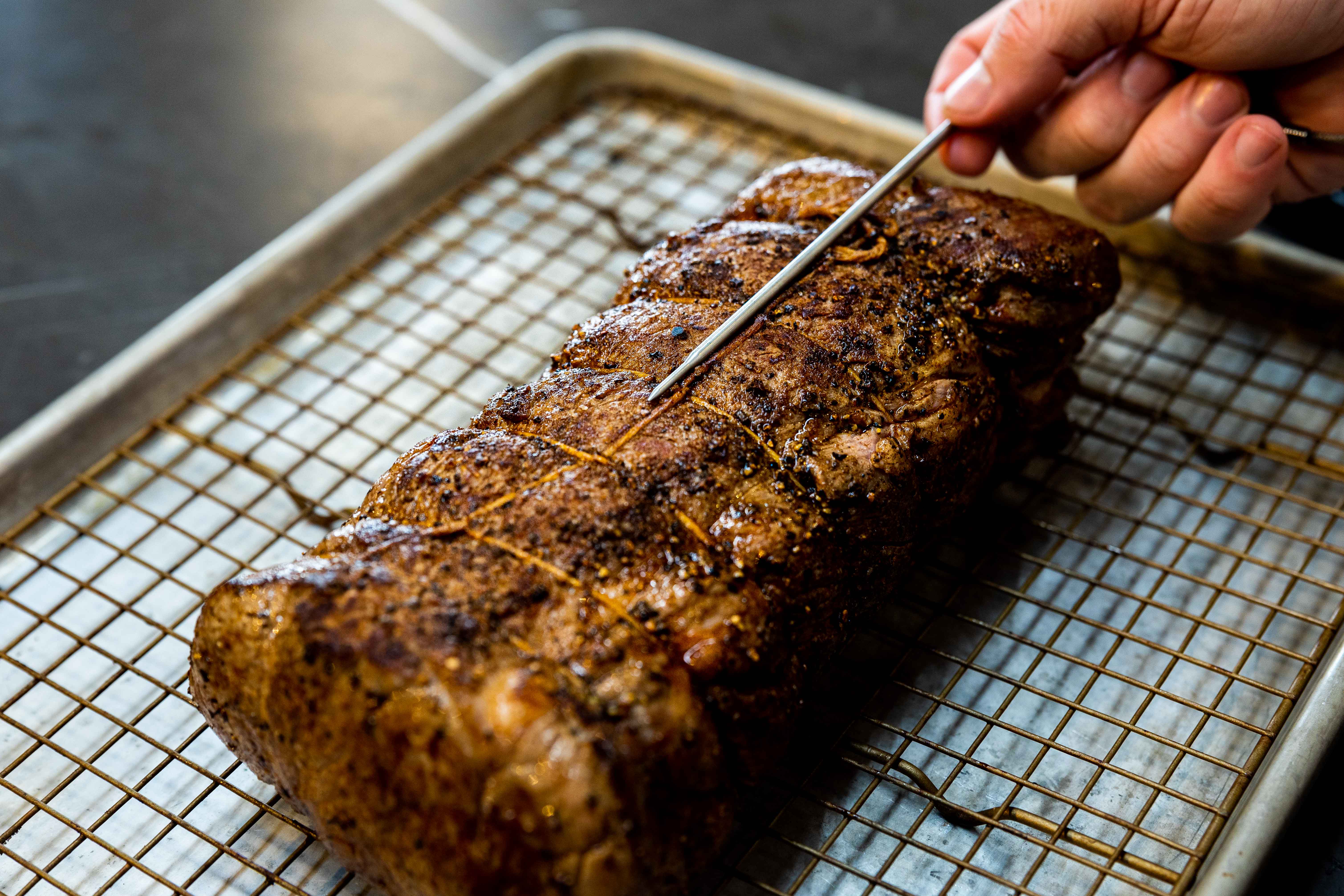 Probing an eye of rib roast with a leave-in thermometer probe