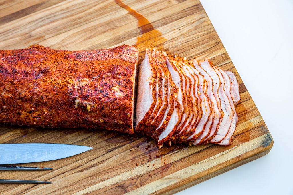 Smoked pork loin with juices dripping across the cutting board