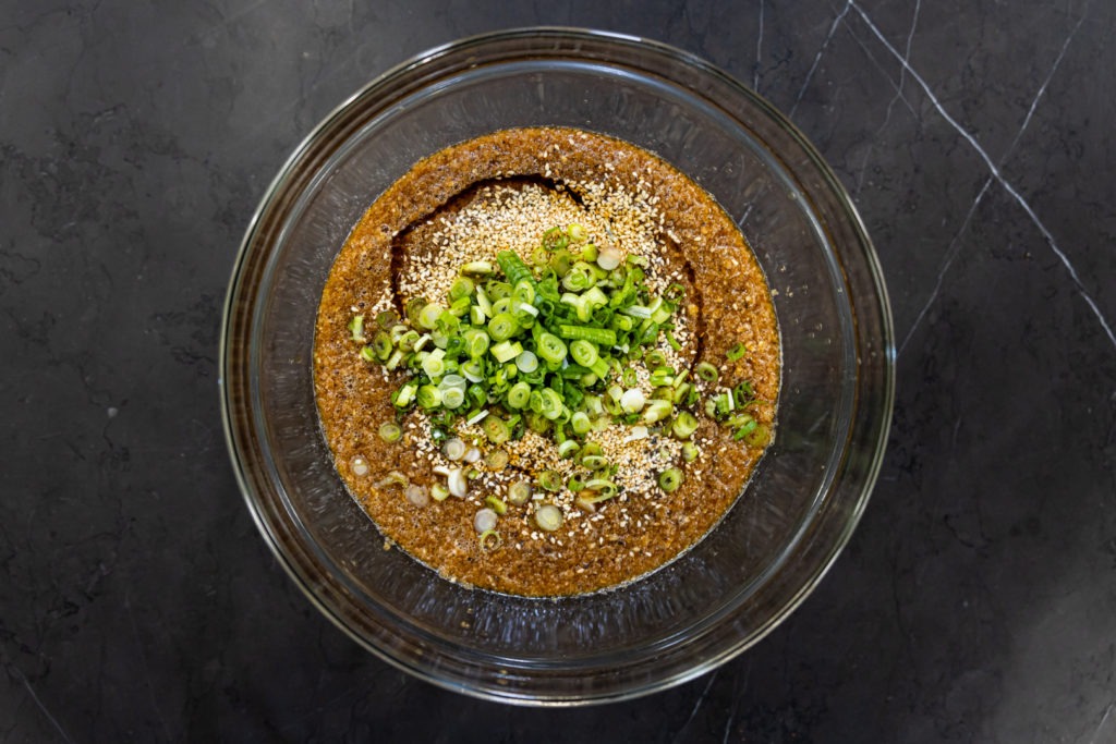 Adding the scallions, sesame sees and sesame oil to the marinade in a bowl