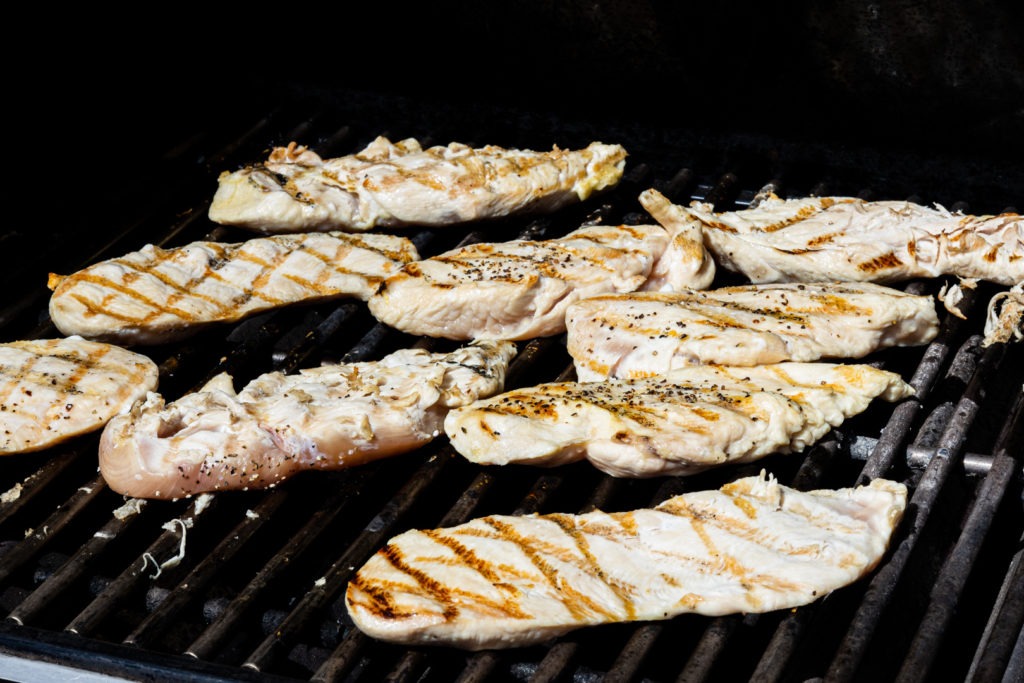 A grill full of half-cooked chicken