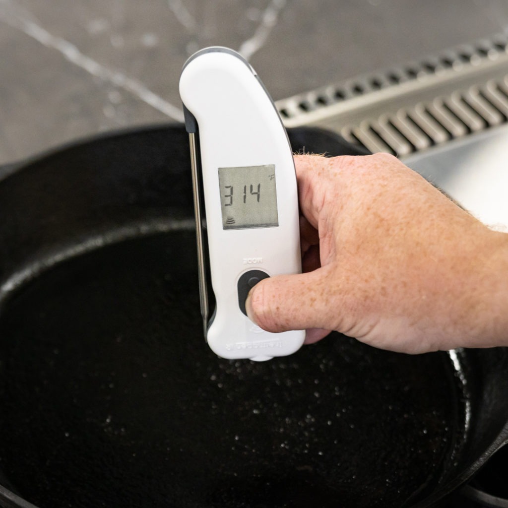 A Thermapen IR temping a cast-iron skillet