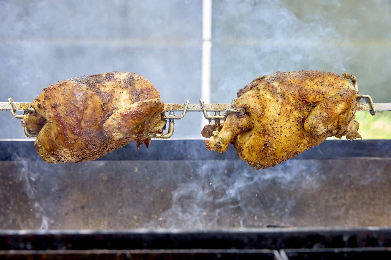 two chickens cooking on a rotisserie