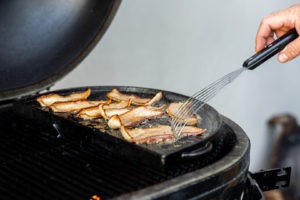 Cooking bacon on a griddle on the grill