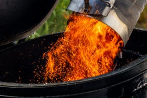 Hot coals dumping into a grill