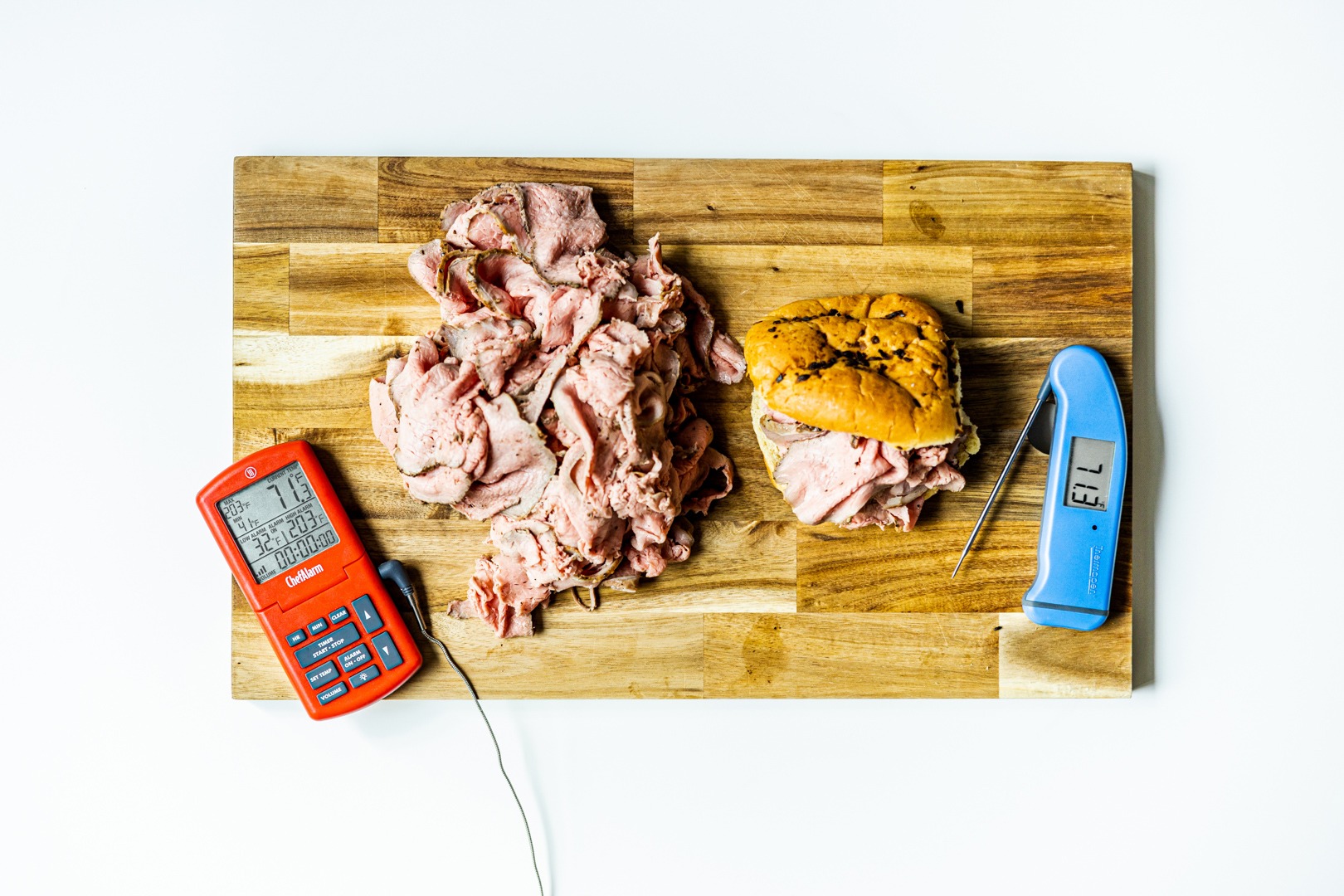 Rosy, perfect roast beef with thermometers on a board with a sandwich