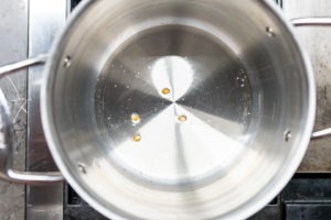 Popcorn kernels in oil at the bottom of a pan