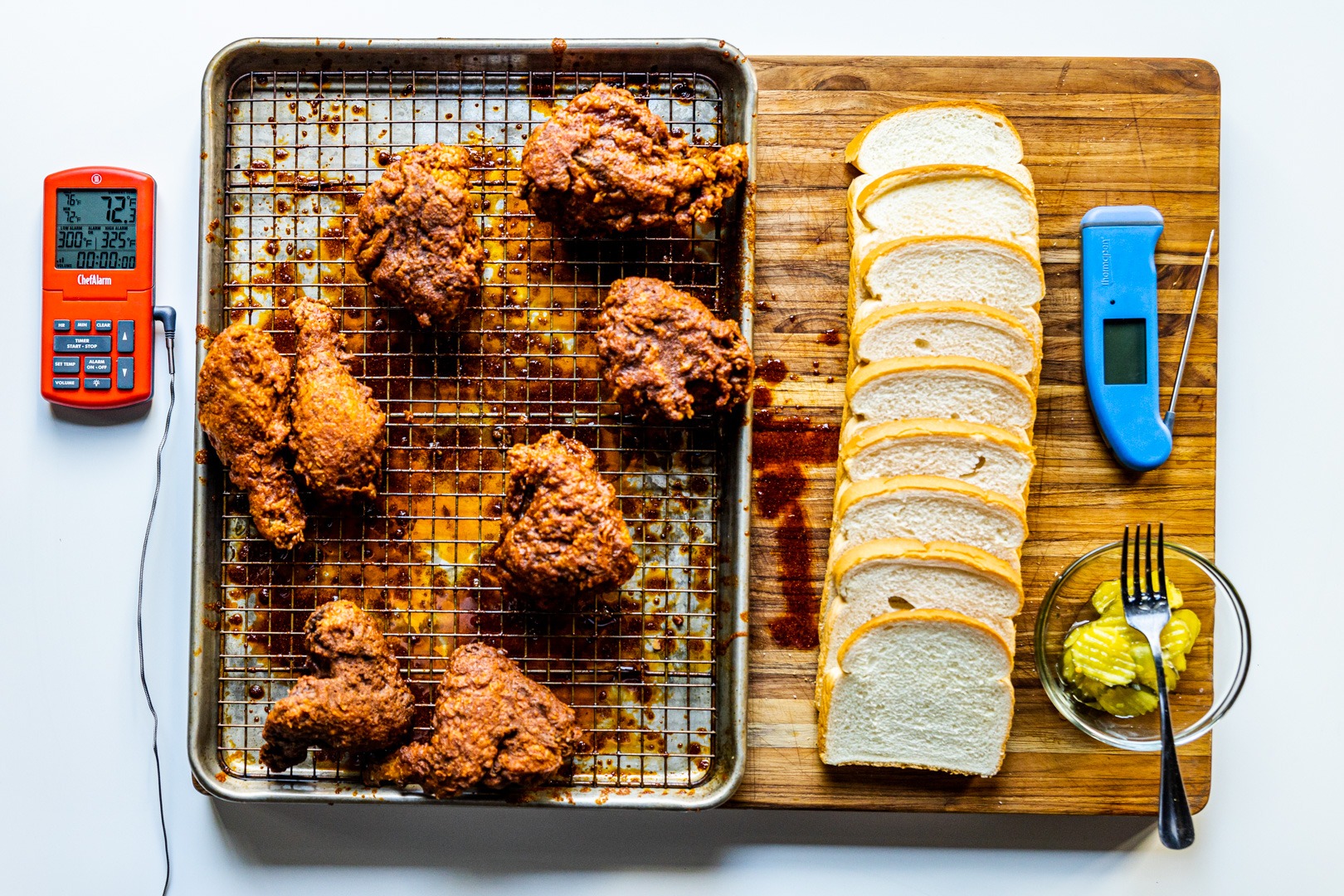 Nashville hot chicken arranged on a board for serving with bread and pickles