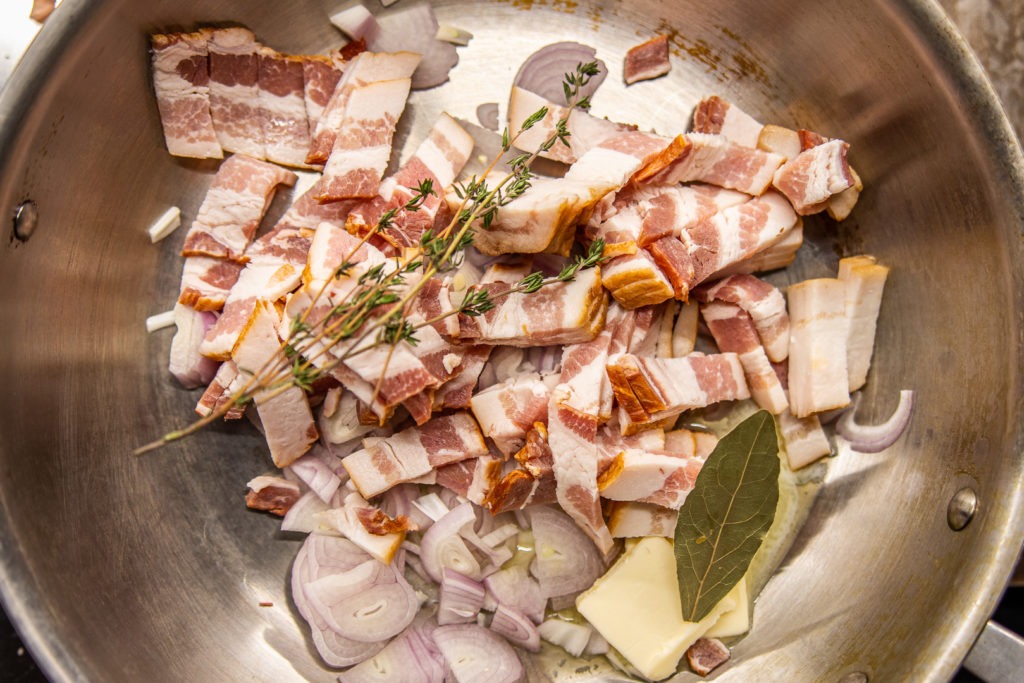 Bacon and herbs and butter in a pan for the quiche filling