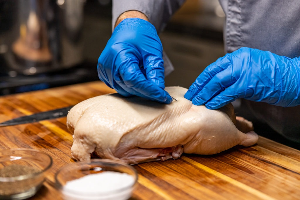 Piercing the skin of the duck with a large needle