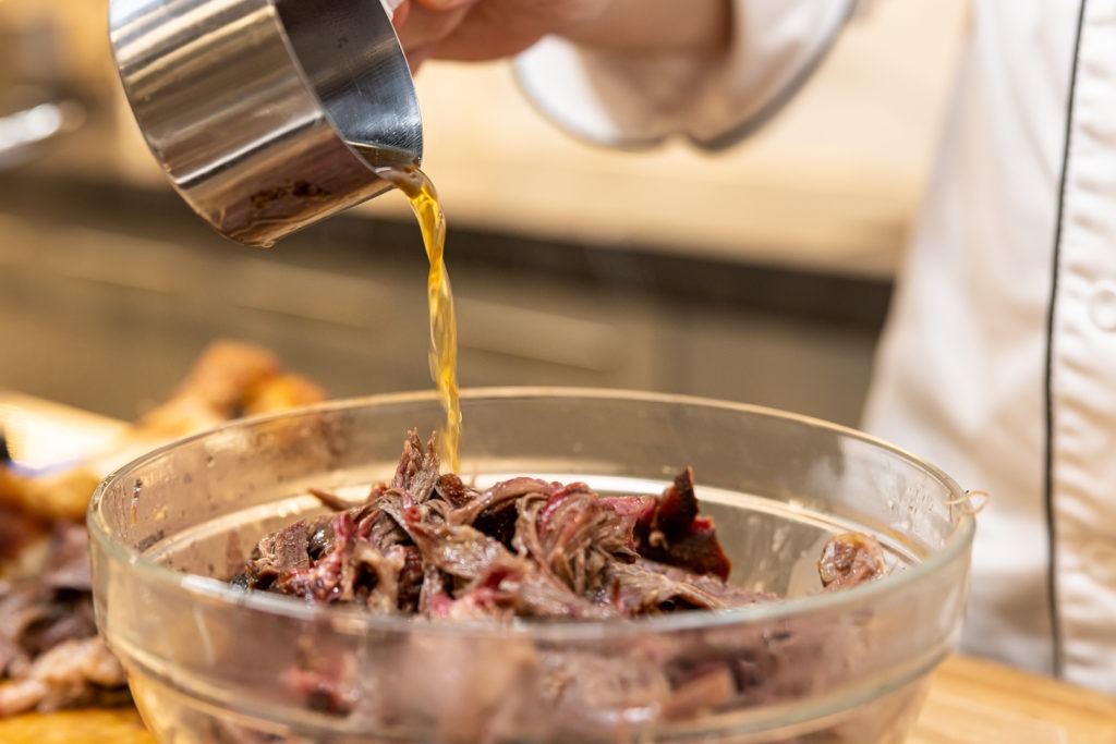 Dousing the shredded beef with its own juices