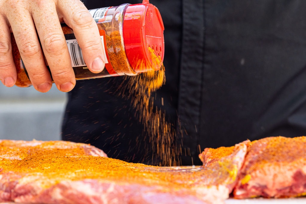 Applying rub to the ribs using a shaker bottle