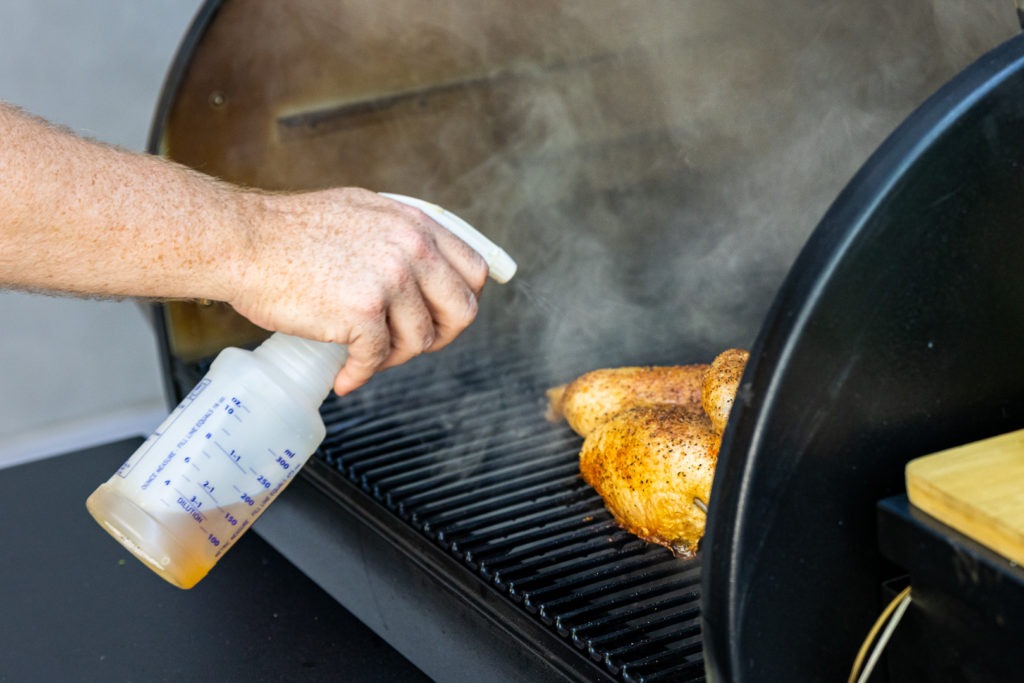 Spritzing the chicken as it smokes