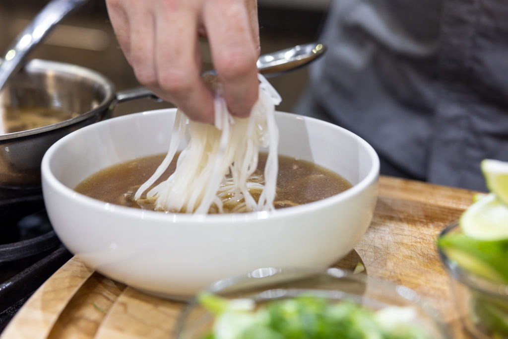 Adding noodles to pho