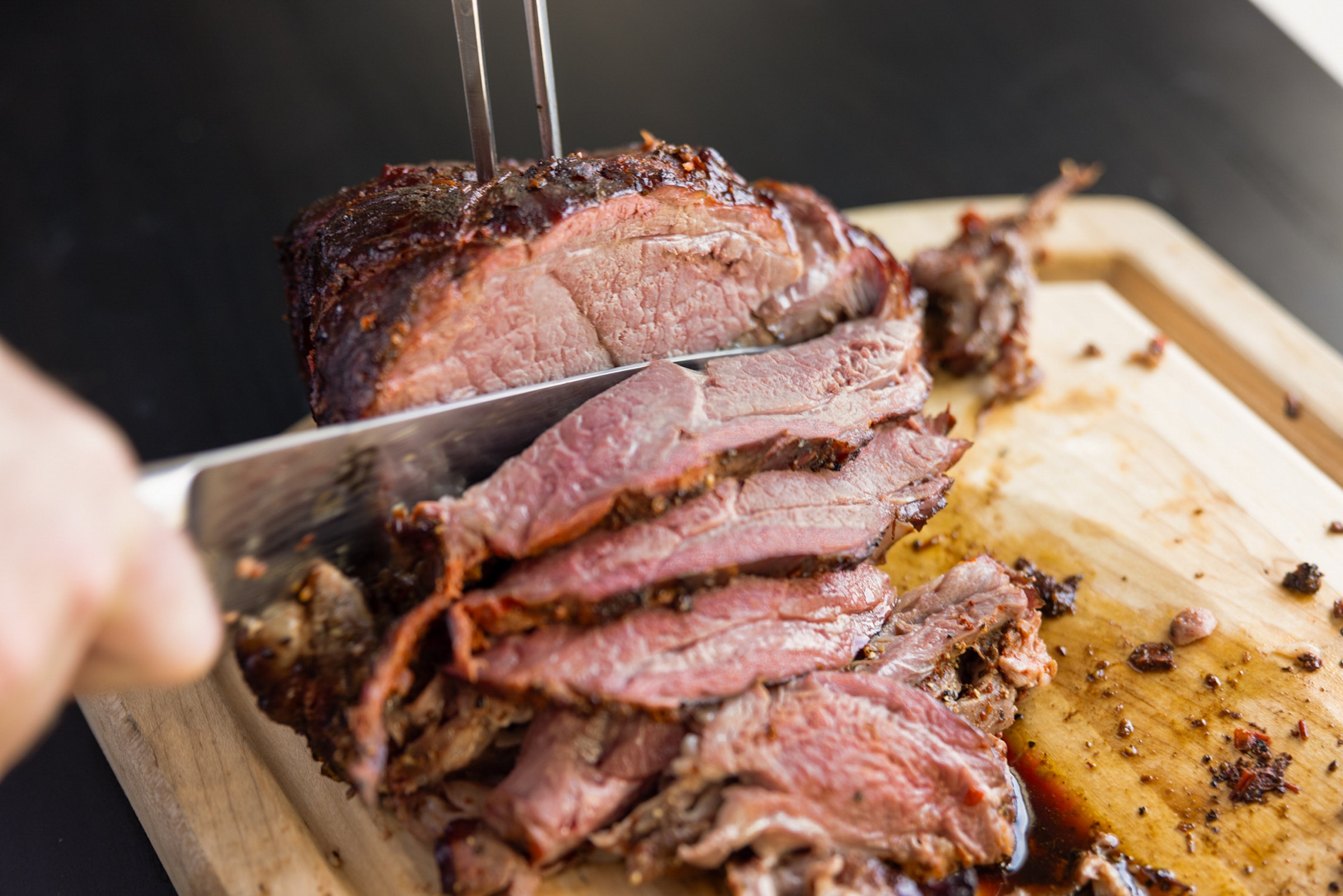 Smoked leg of lamb being sliced on a cutting board