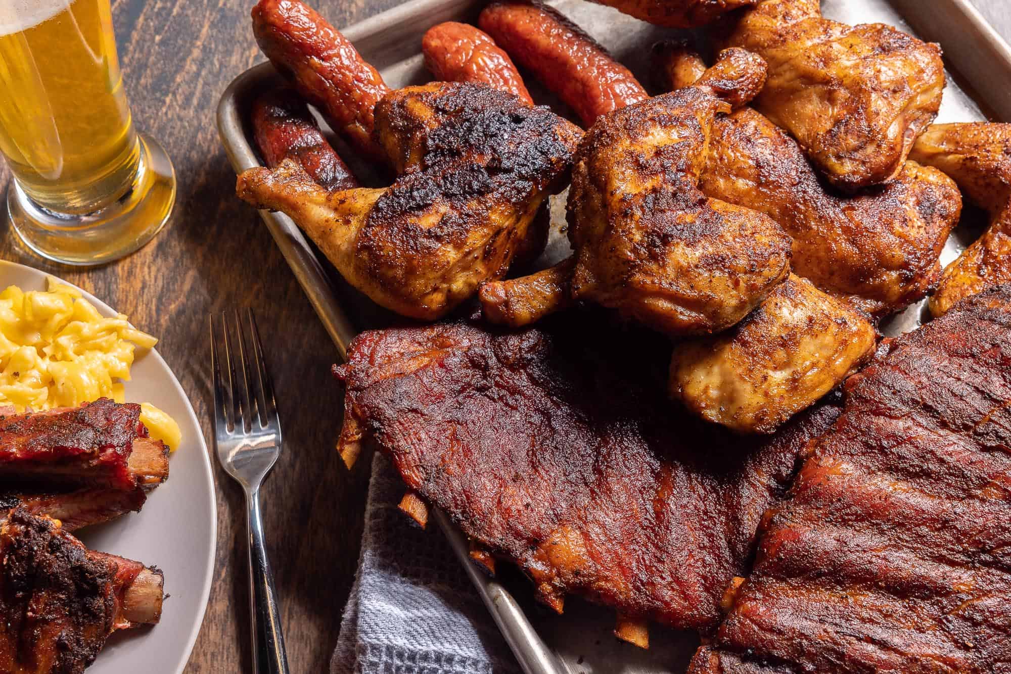 A large platter of ribs, chicken, and sausage