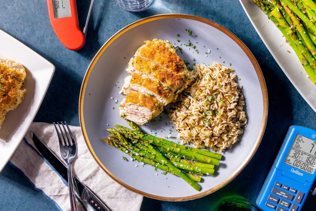 A chicken cordon bleu dinner with asparagus, rice, and thermometers