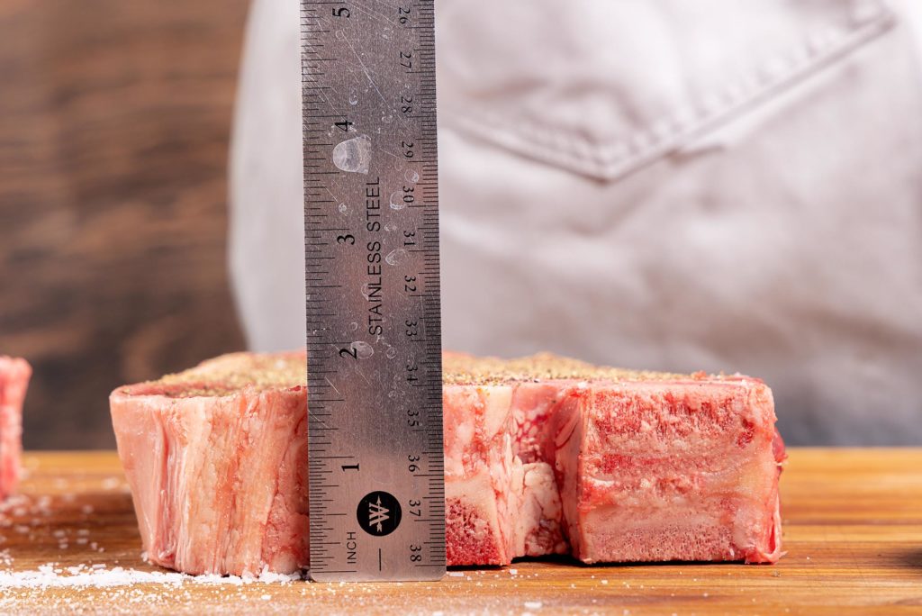 steak lying on board with ruler showing thickness just greater than 1.5"
