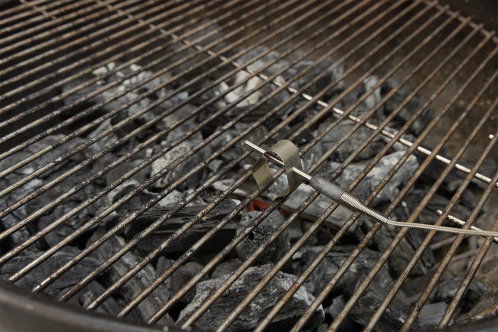 A probe in a grate clip on the surface of a grill
