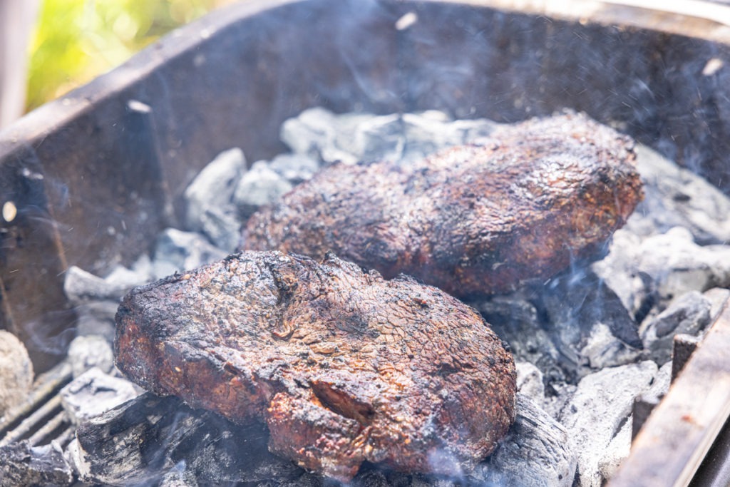 steaks cooking on coals