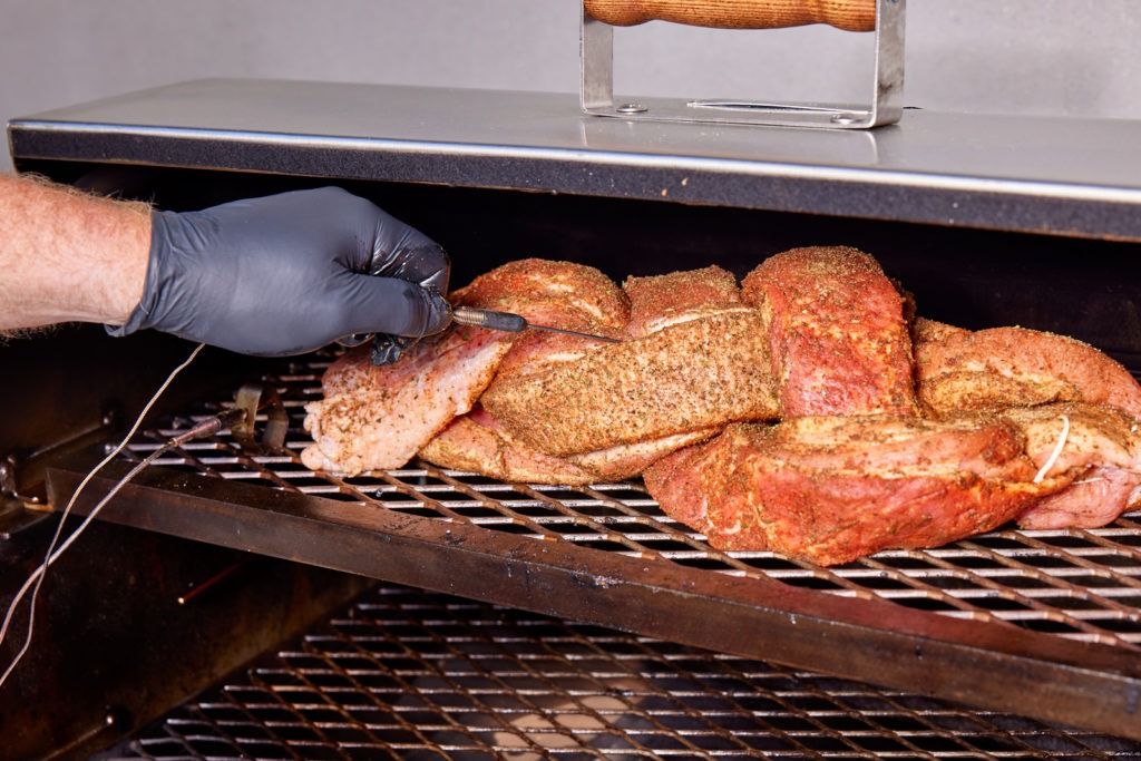 Inserting a probe into the meat on the smoker