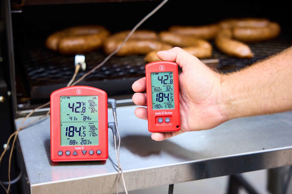 Thermometer in front of sausages on a smoker