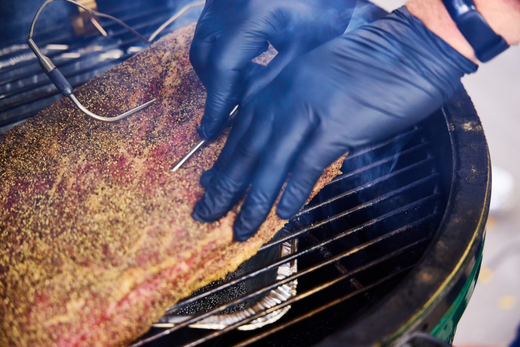 Inserting a probe into the brisket set over a water pan