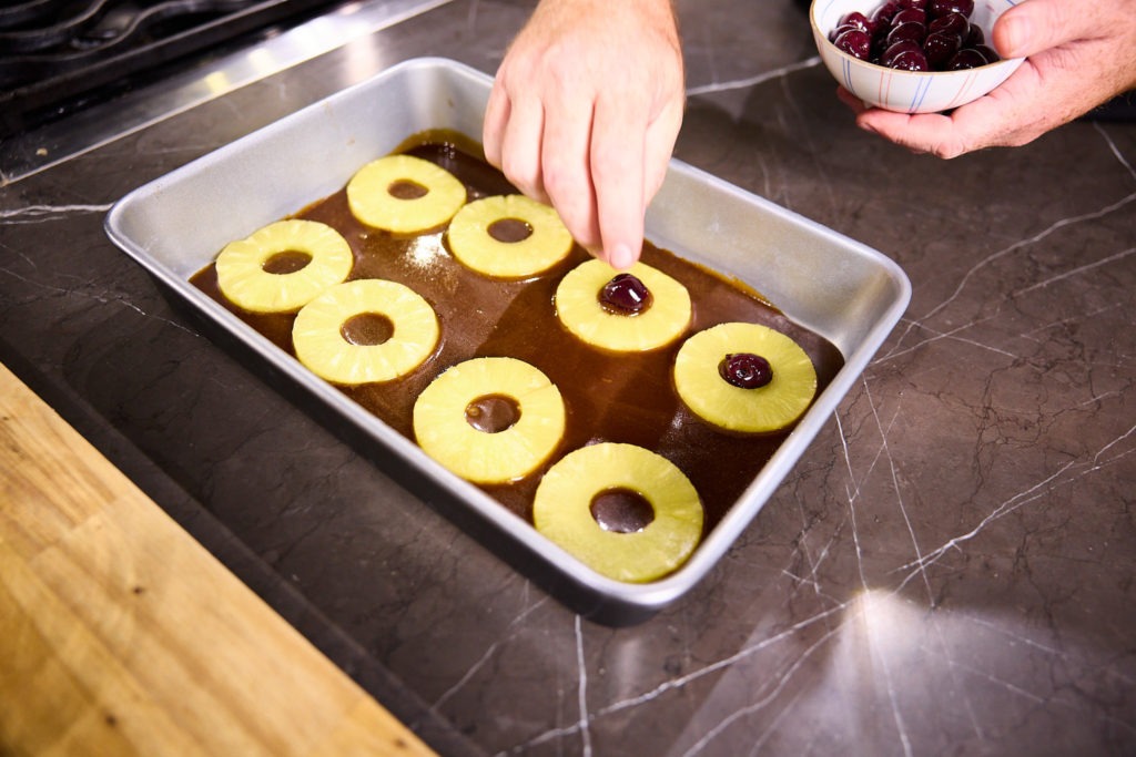 Placing pineapple and cherries in caramel
