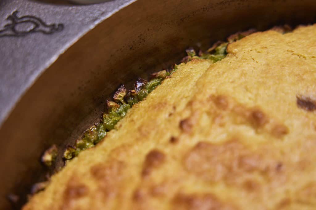 The crispy edges of the cornbread against the cast-iron skillet