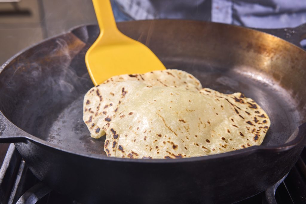 Taking a puffed up tortilla from the pan. 