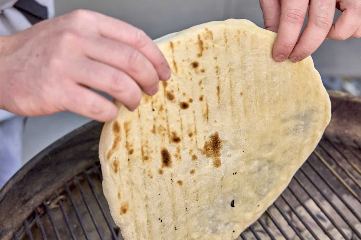 picking up the grilled, half-cooked dough