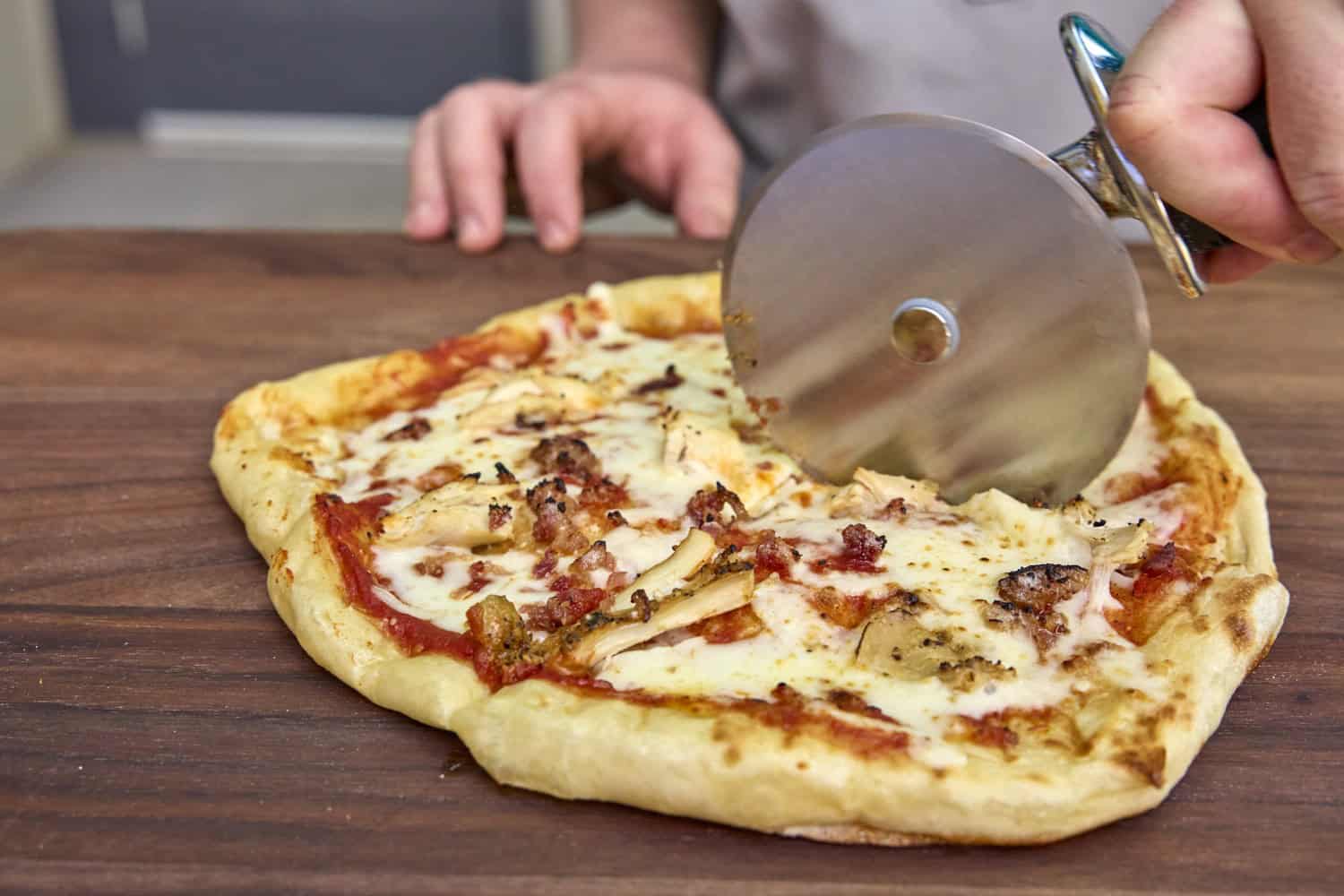 slicing grilled pizza