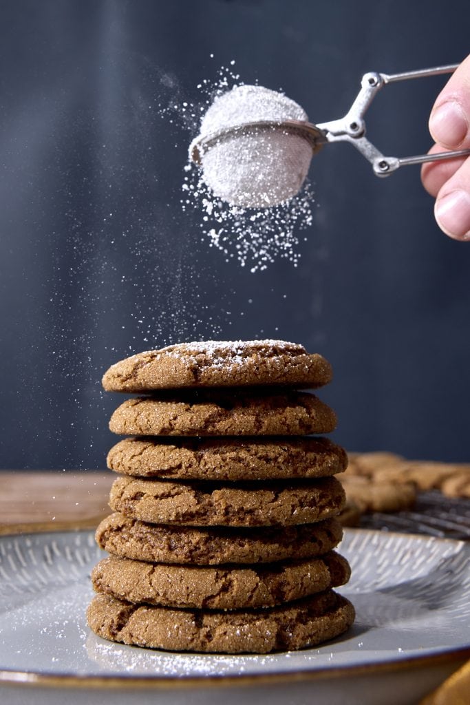 a stack of cookies being powdered with confectioner's sugar