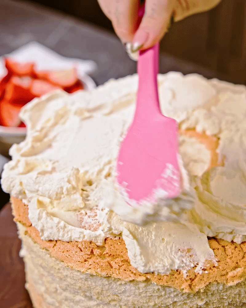adding whipped topping to the angel food cake