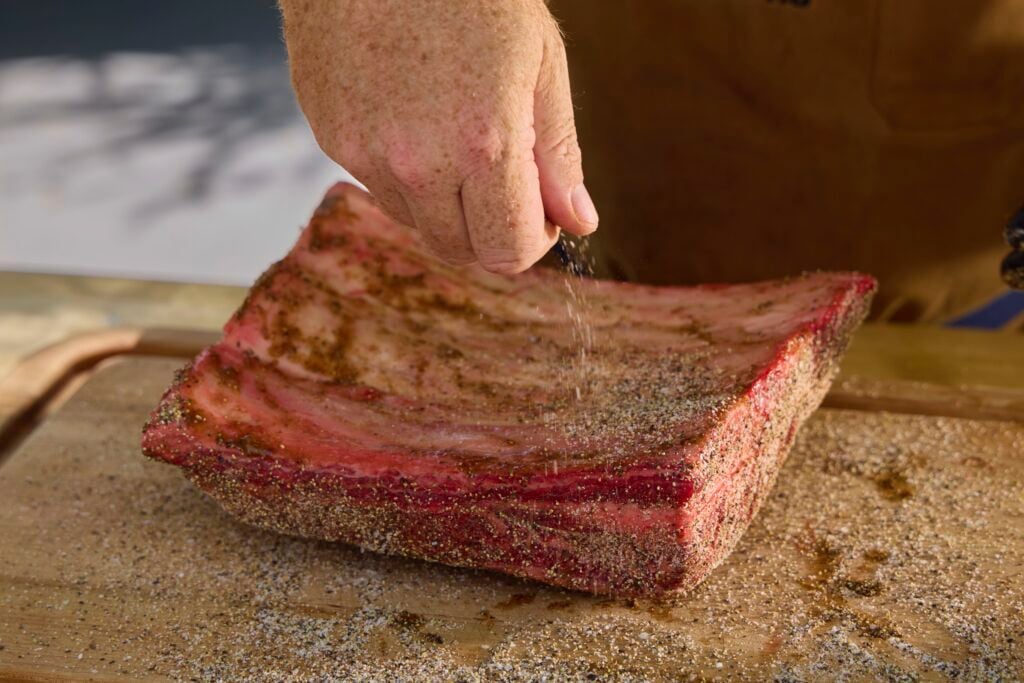 seasoning a plate of dino ribs
