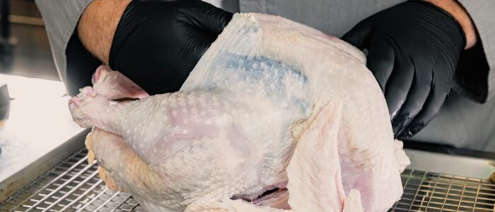 separating the kin form the meat by putting a gloved hand up under the skin of the breast