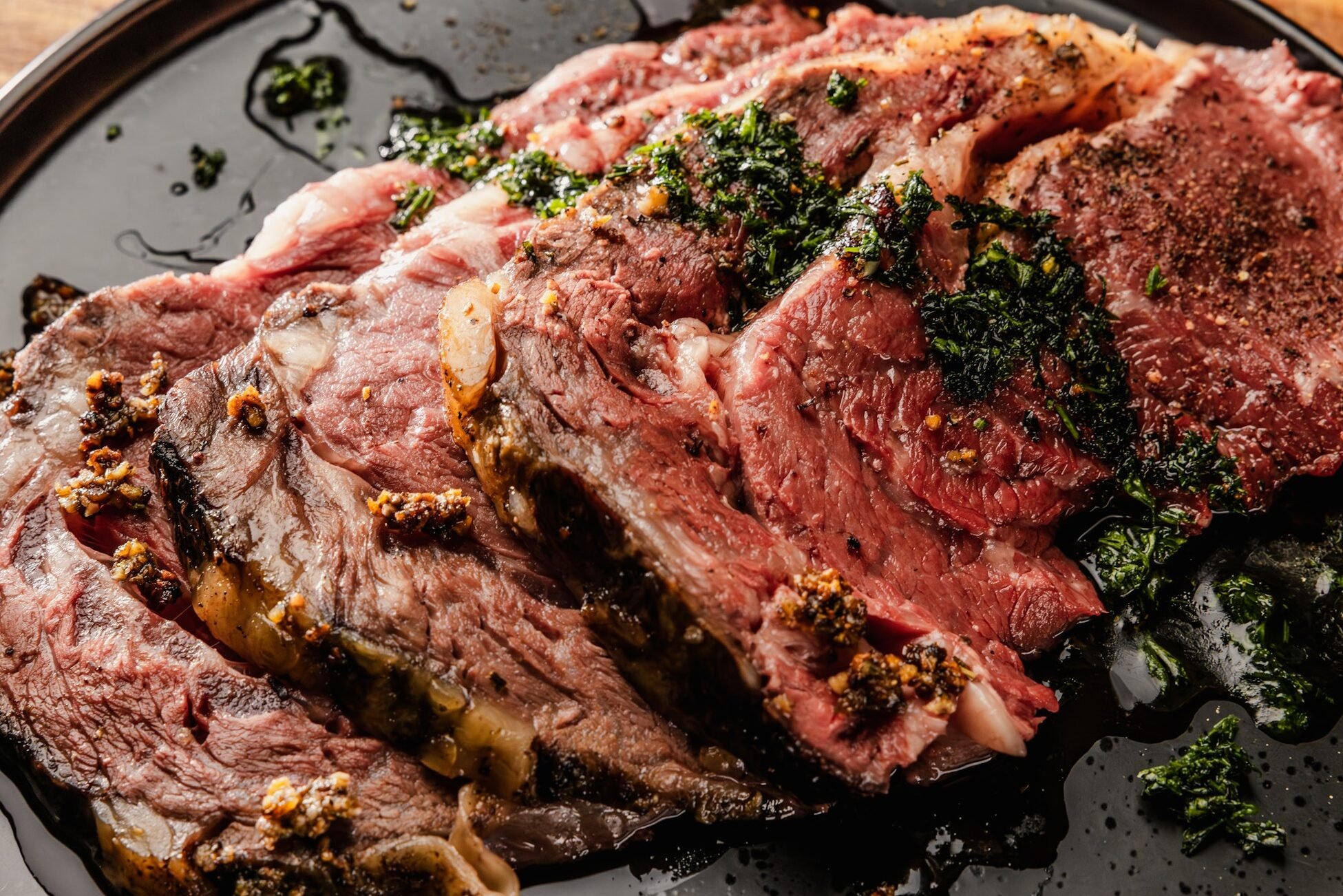 Sliced prime rib on a plate with chimichurri