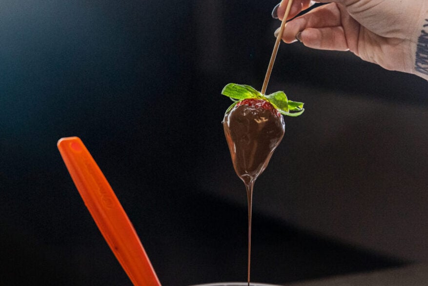 chocolate dipped strawberry with chocolate dripping off fruit. black background